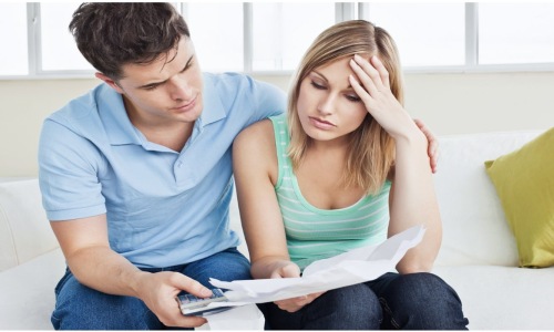 A worried couple reviewing bills and calculating rent payments while applying for an apartment in Los Angeles.